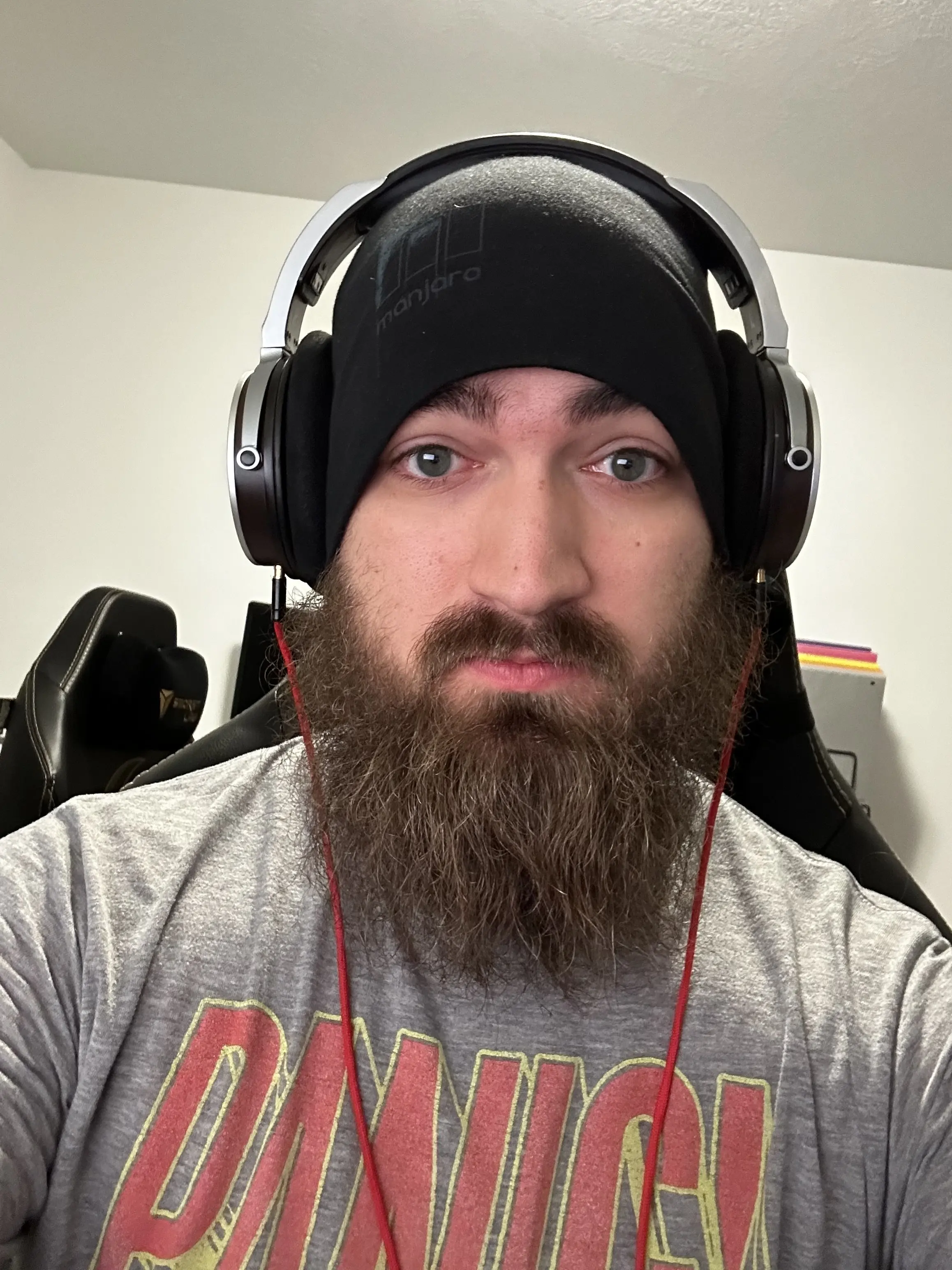 Jacob Banghart smiling in a Manjaro beanie, headphones, sitting in a chair.